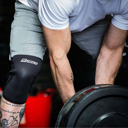 Loading up a barbell preparing for a liftin in the Black V2 7mm knee sleeves